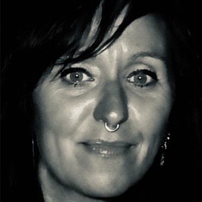 Monica Rosenville portræt – kvinde ser frem mod kamera med neutralt udtryk, lys baggrund.